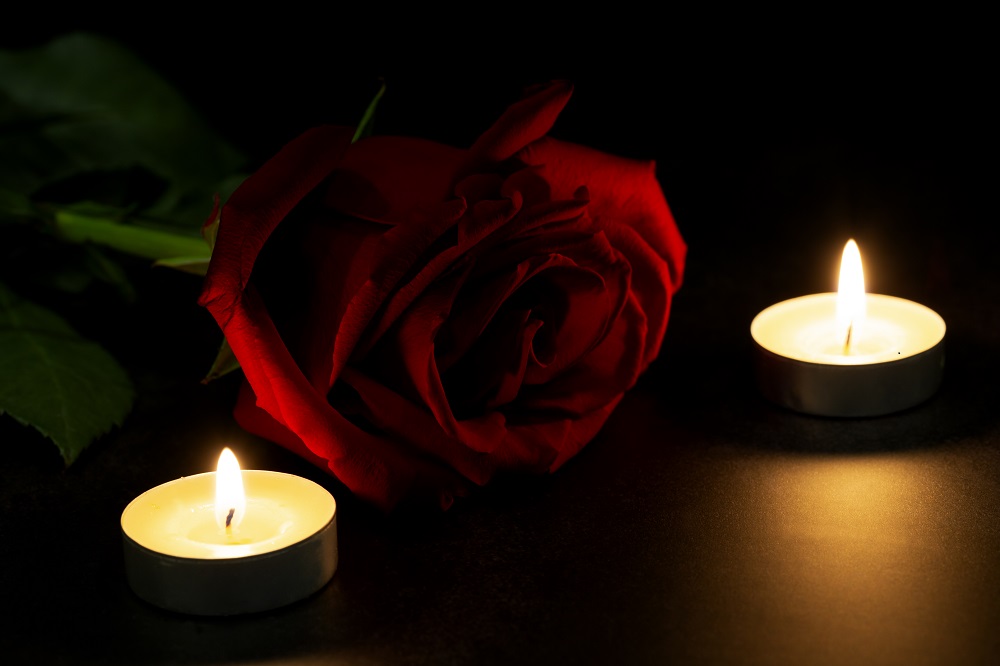 Rosa roja junto a dos velas