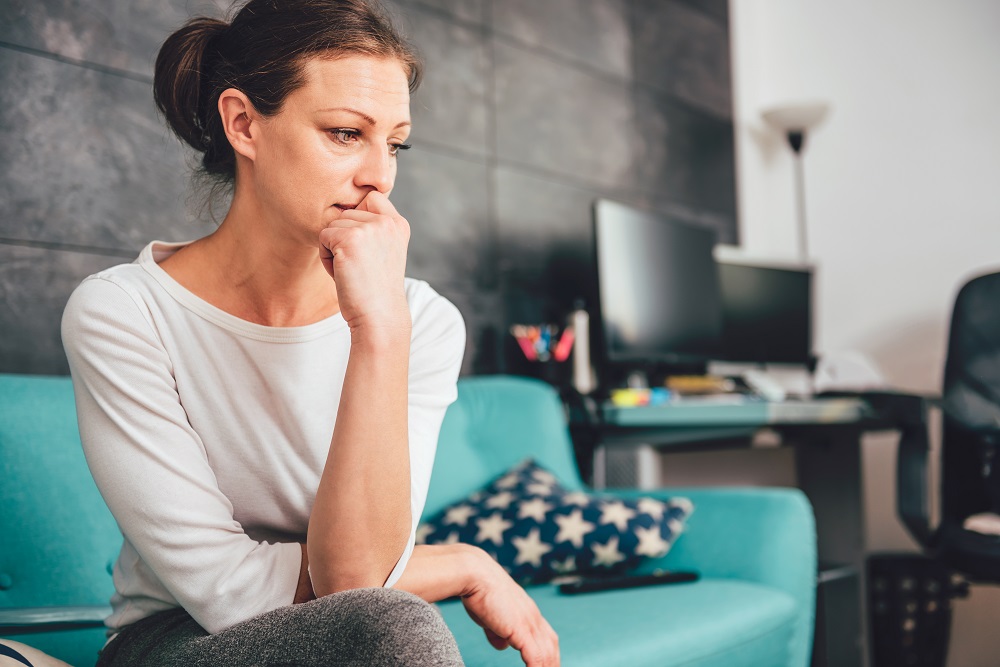 Mujer triste sentada en sofá /Piensa: mi esposo embarazó a su amante